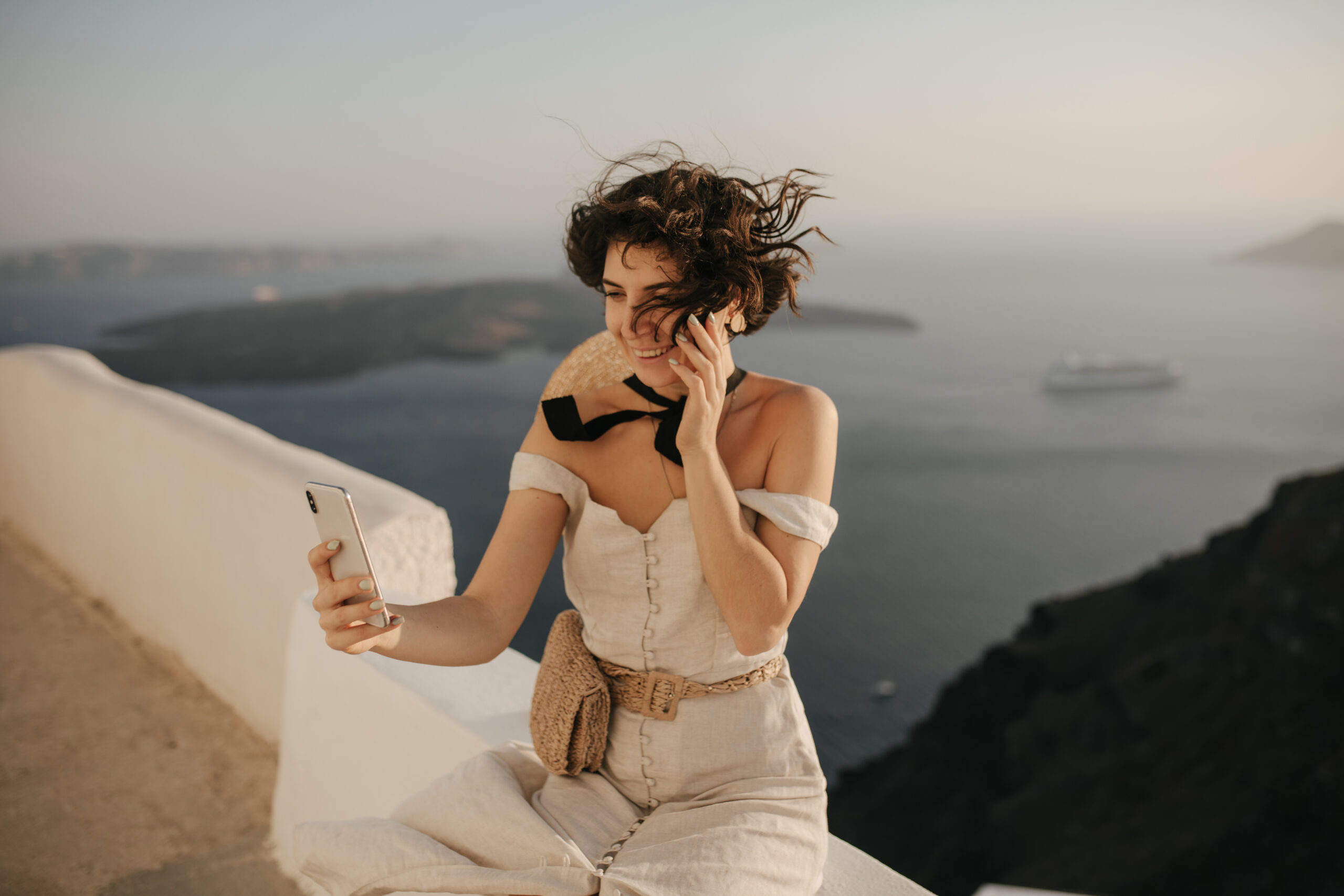 Woman using her phone with the sea in the background