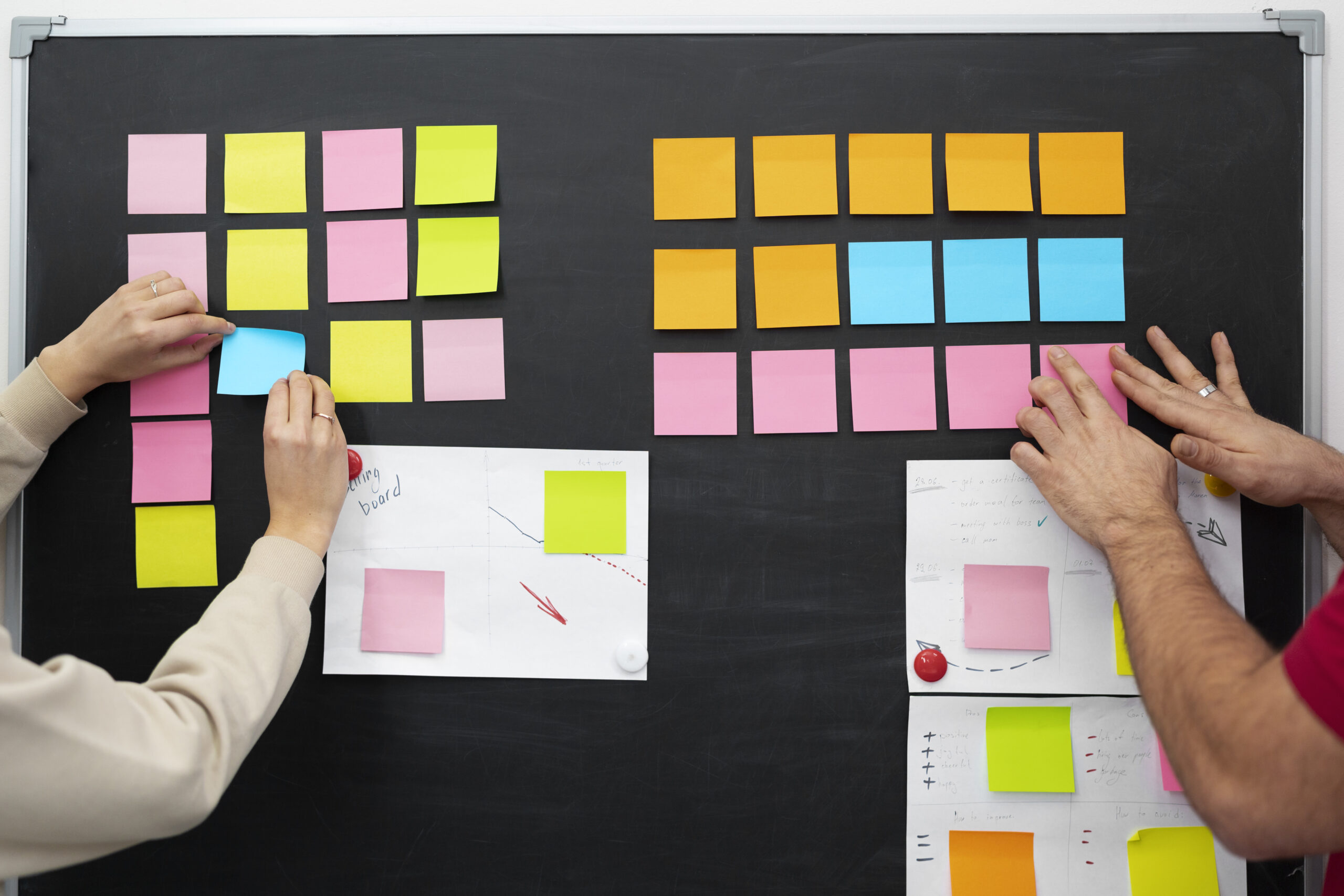Hands arranging colorful sticky notes on a board