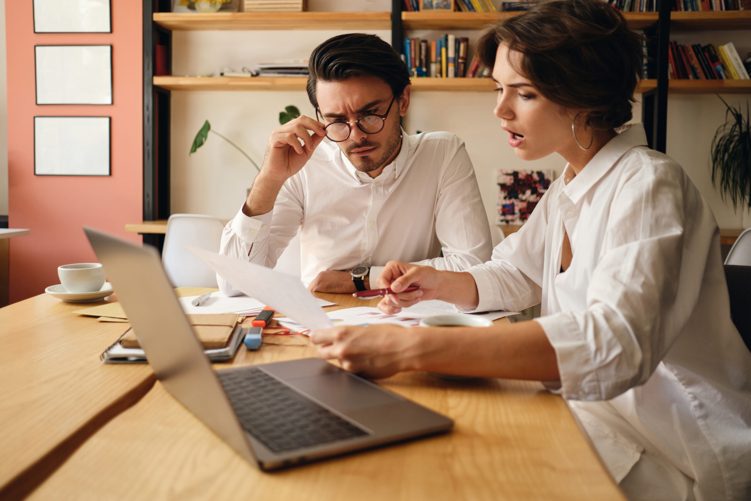 Colleagues talking over a laptop and documents in an office